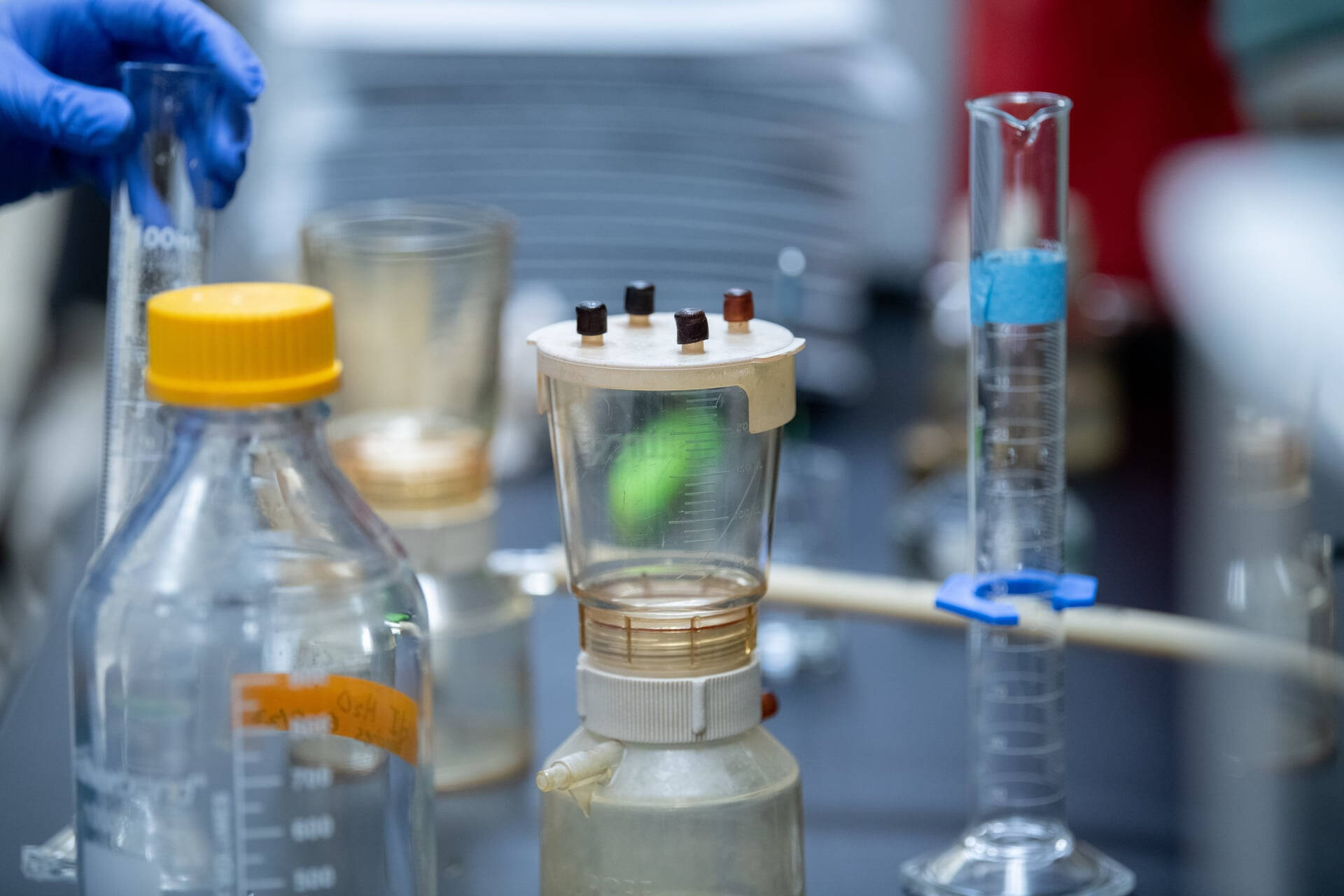Student with graduated cylinder in the lab pouring into funnel.